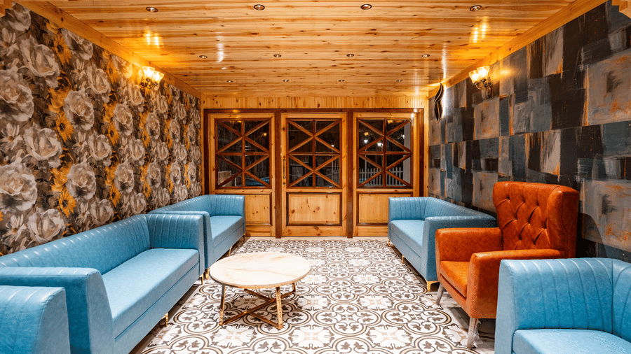 A stylish indoor lounge area with light blue sofas, an orange armchair, and patterned flooring - Golden Oak By The Lake Hill, Khurpatal