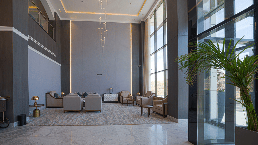 Natural light entering the lobby area of Grand Iva Hotel, Abha, through large glass windows, and lighting up the upholstered sofas.