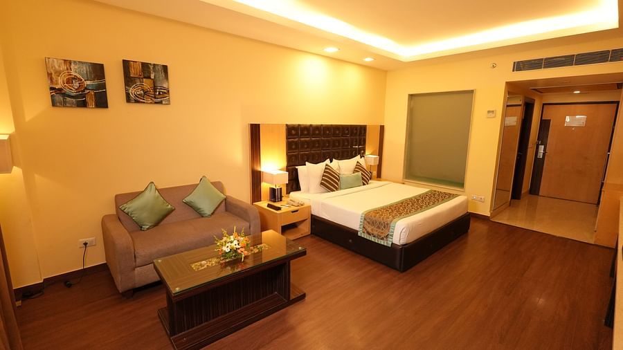 Hotel suite with a bed, seating area, coffee table, and warm ambient lighting - Grand Plaza Lords Inn Jammu