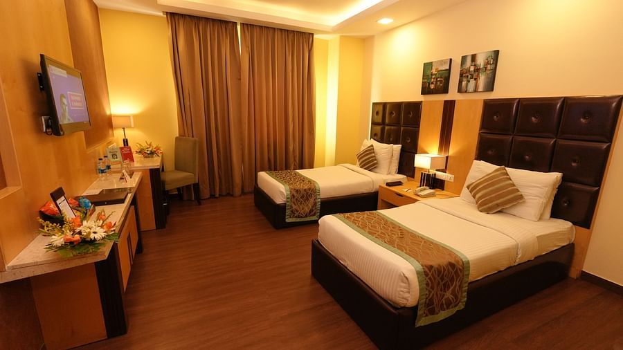 Hotel room with DOUBLE bed, seating area, warm lighting, and dark wood furniture - Grand Plaza Lords Inn Jammu