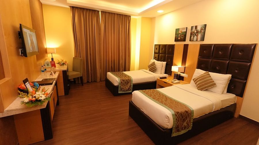 Hotel room with two beds featuring patterned bedding and warm lighting fixtures - Grand Plaza Lords Inn Jammu