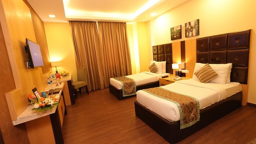 Hotel room showcasing two beds, a desk, and a television mounted on the wall - Grand Plaza Lords Inn Jammu