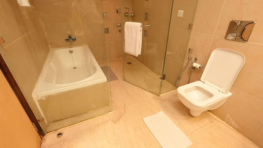 Bright bathroom with a bathtub, toilet, white towels, and a tiled floor - Grand Plaza Lords Inn Jammu
