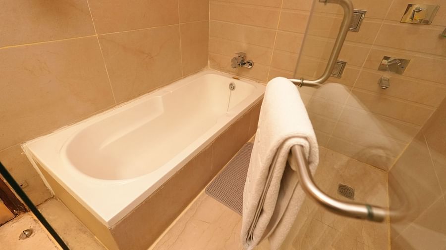 Modern bathroom featuring a bathtub with a chrome handle and white towels - Grand Plaza Lords Inn Jammu