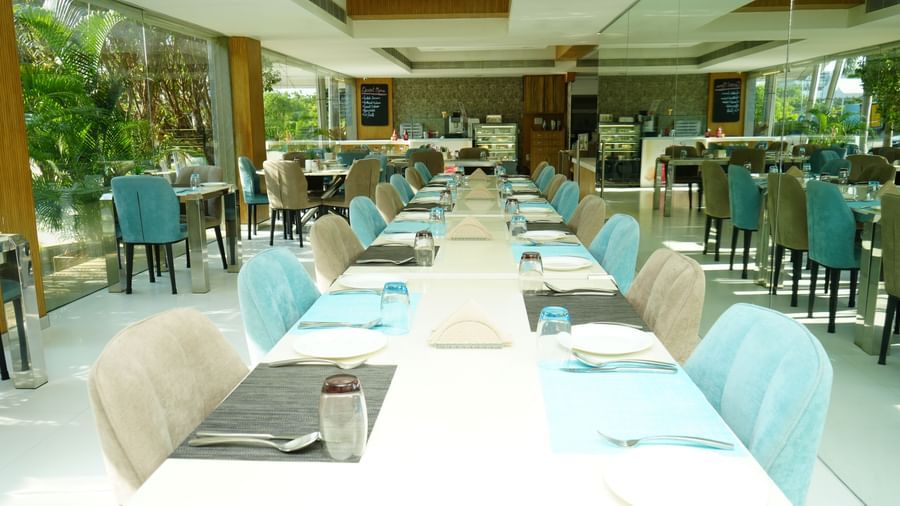 Long dining tables with blue chairs set inside a well-lit restaurant.Long dining tables with blue chairs set inside a well-lit restaurant at  Grande Bay Resort & Spa.