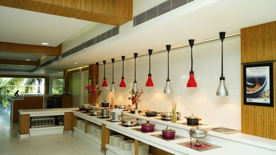 A buffet counter with food containers and hanging red lamps above at Grande Bay Resort & Spa.