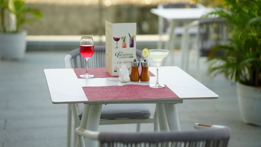 Outdoor tables set with a glass of red drink, cutlery and menu cards at Grande Bay Resort & Spa.