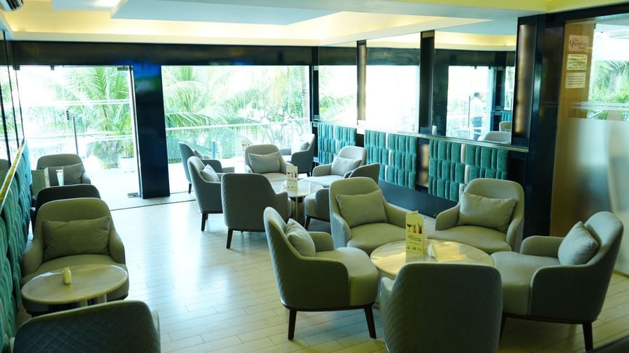 Indoor lounge area with armchairs and tables arranged in rows at Grande Bay Resort & Spa.