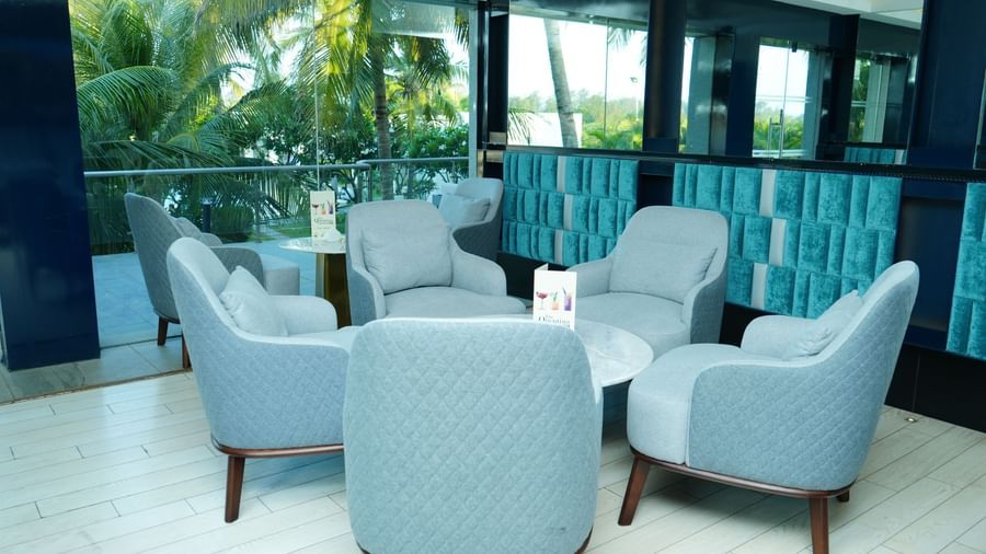Indoor seating area with armchairs and tables beside large windows at Grande Bay Resort & Spa.