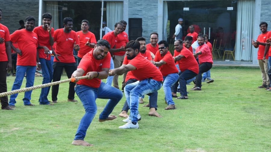 Group of people with red t-shirts pulling on opposite ends of a rope competing for a tug of war game at Grande Bay Resort & Spa.