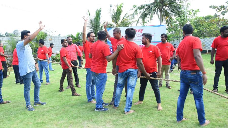 Group of people wearing red t-shirts standing with a rope on their hand in an outdoor space at Grande Bay Resort & Spa.