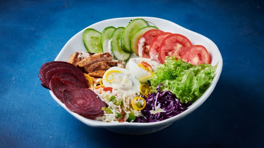 A bowl of fresh salad with sliced cucumber, tomato, beetroot, lettuce, and dressing at Grande Bay Resort & Spa.