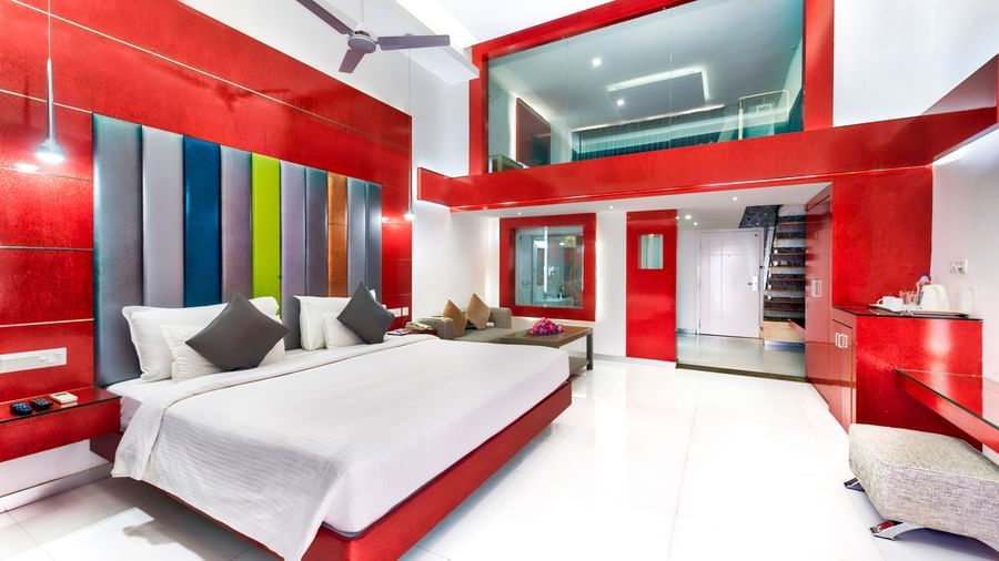 A room with a king size bed, colourful headboard, red and white decor, and seating area at Grande Bay Resort & Spa