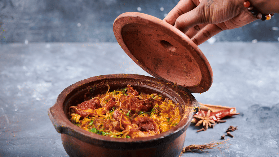 Clay pot being opened to reveal aromatic biryani garnished with herbs and spices - Grande Bay Resort & Spa, Mamallapuram