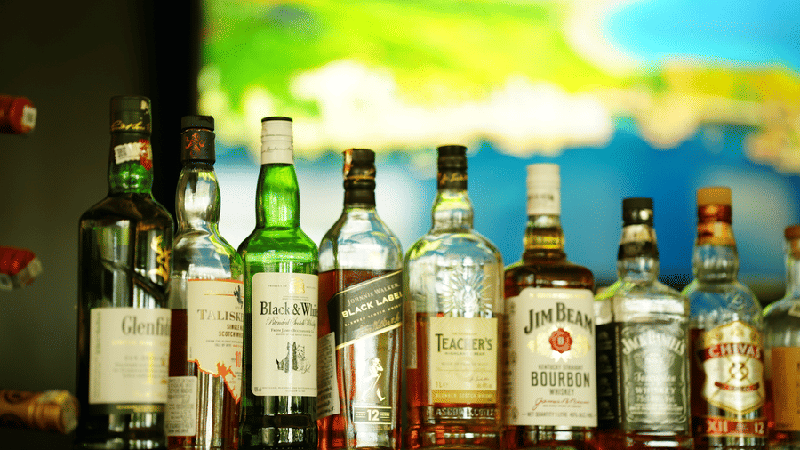 Liquor display at The Quentina Bar showcasing premium bottles arranged on a back-lit shelf - Grande Bay Resort & Spa, Mamallapuram