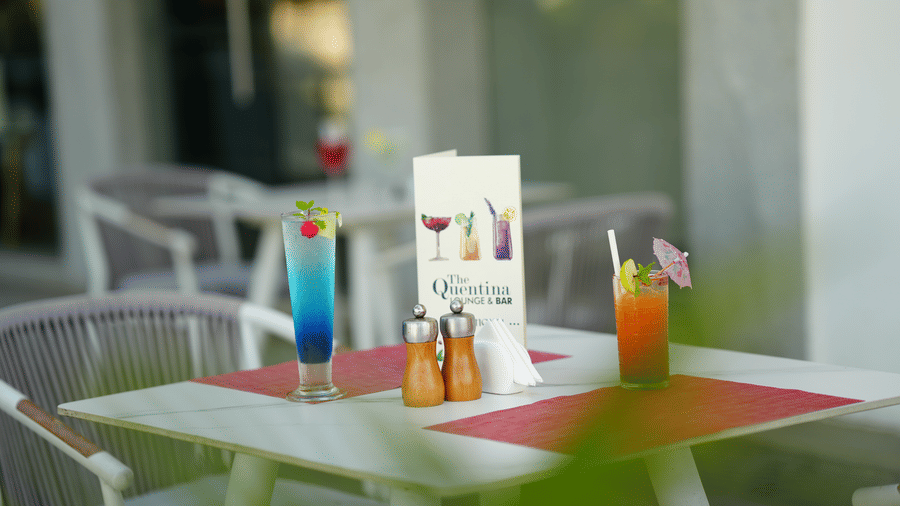 Drinks and menu card placed on an outdoor dining table with chairs at Grande Bay Resort & Spa.