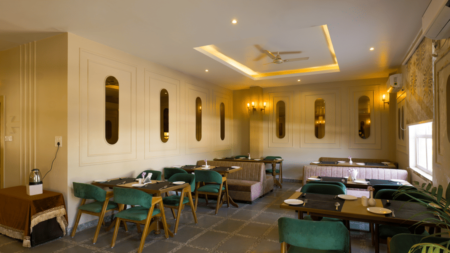 A large dining area with wooden tables and upholstered chairs arranged under a decorative ceiling at Grassfield Riveria Resort.