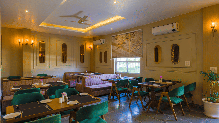 A restaurant interior showing multiple table setups and a large window with a patterned blind at Grassfield Riveria Resort.