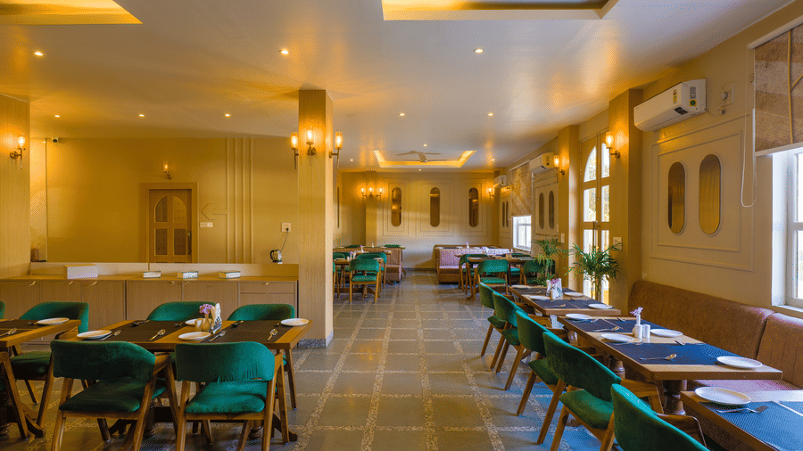 An interior shot of Amaya Restaurant with wooden tables and upholstered chairs under warm lighting at Grassfield Riveria Resort.