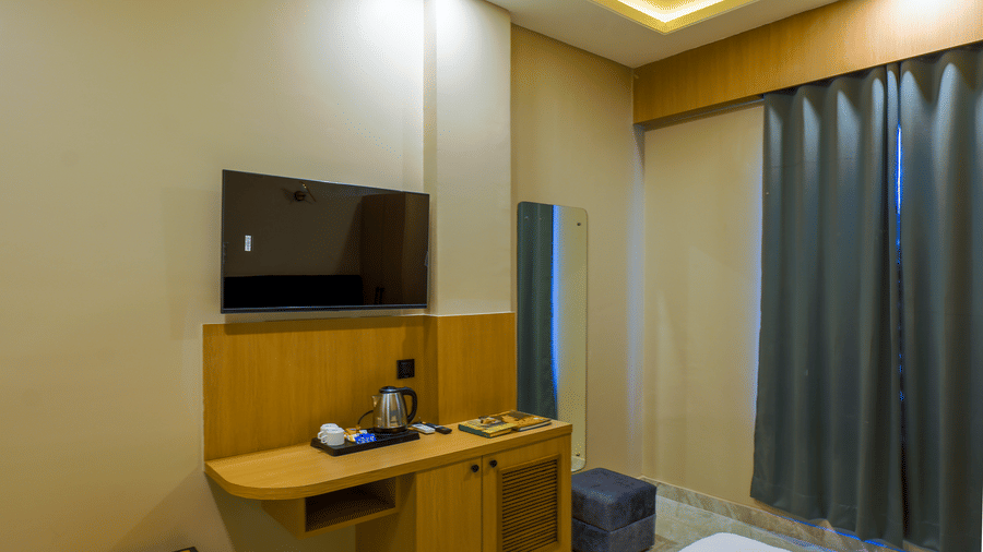 A room Grassfield Riviera Resort, with a television on a stand, an accent wall, and curtains.