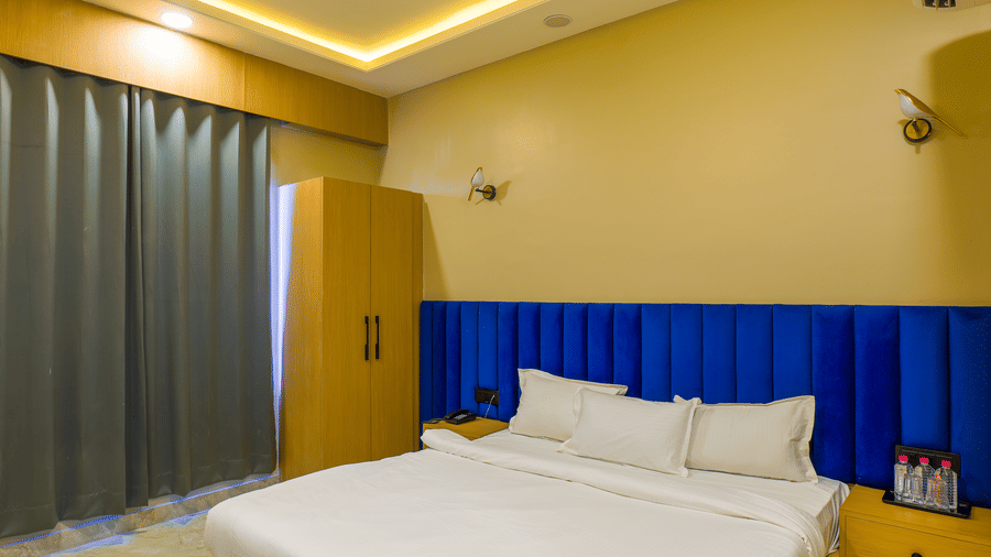 A room at Grassfield Riviera Resort, with a large bed, a headboard, and a wooden wardrobe.