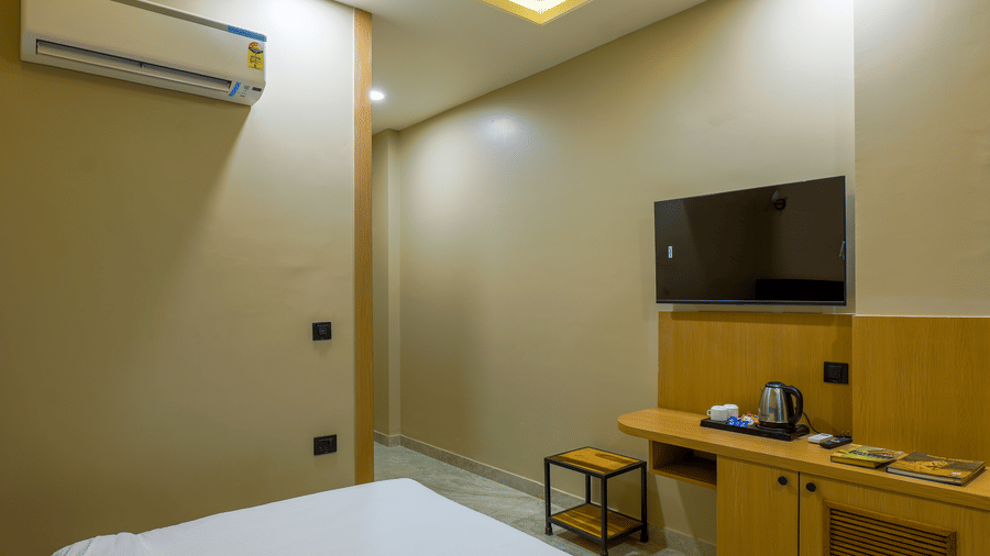 A room at Grassfield Riviera Resort, featuring a bed, a wall mounted air-conditioner, a television, a table, and a chair.