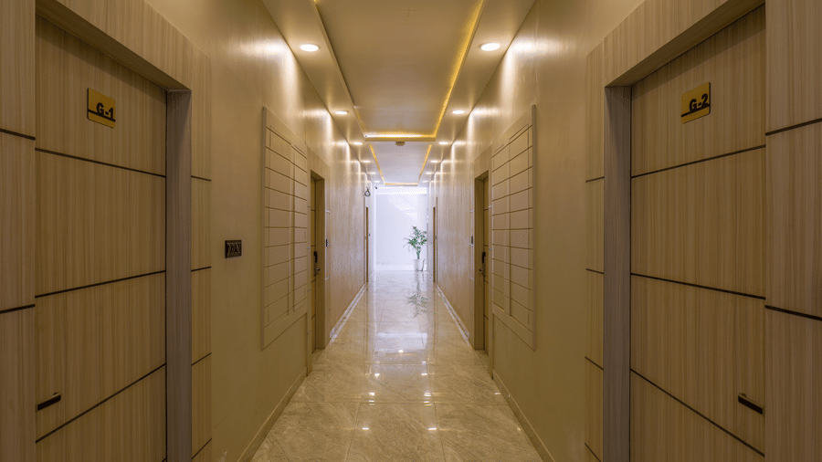 A well-lit hotel corridor with several closed wooden doors on both sides at Grassfield Riveria Resort.