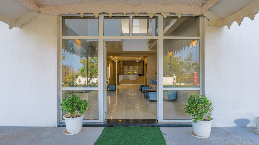 An entrance with glass doors featuring a welcome mat and 2 potted plants on either side at Grassfield Riveria Resort.
