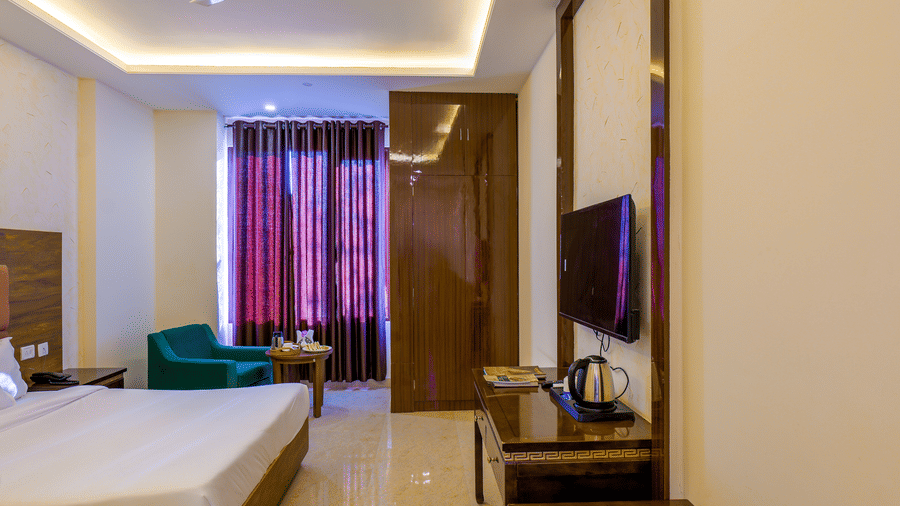 The Premium Room featuring a double bed, a desk with a television, and a window with curtains at Grassfield Riveria Resort.