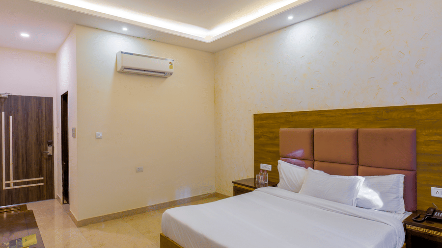 The Premium Room with a double bed and an air conditioning unit mounted on a plain wall at Grassfield Riveria Resort.