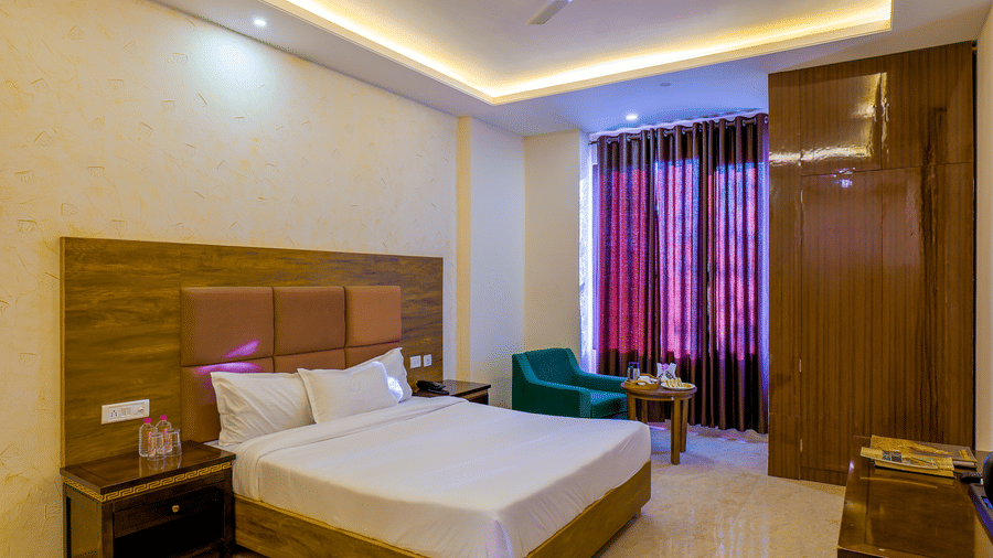 The Premium Room featuring a large bed with a padded headboard and a small seating area by a window at Grassfield Riveria Resort.