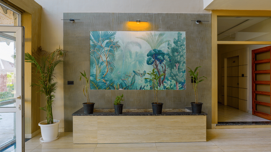 A wide shot of a modern minimalist building interior featuring a large nature-themed mural on a central wall and indoor potted plants at Grassfield Riveria Resort.