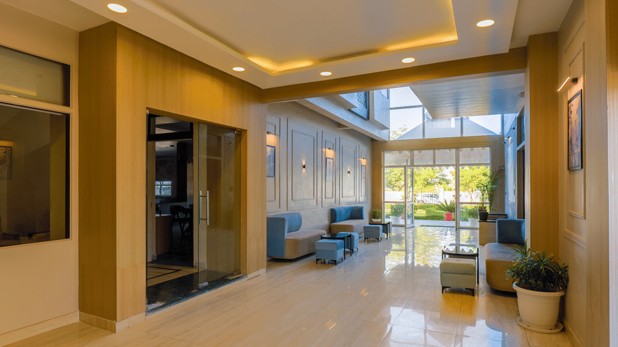 An interior shot of the lobby highlighting the tray ceiling with warm recessed lighting and large windows at the far end at Grassfield Riveria Resort.