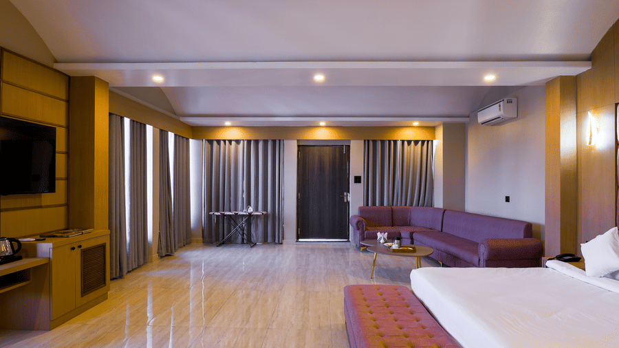 The spacious Suite with a double bed and a long sofa under a flat ceiling with recessed lighting at Grassfield Riveria Resort.