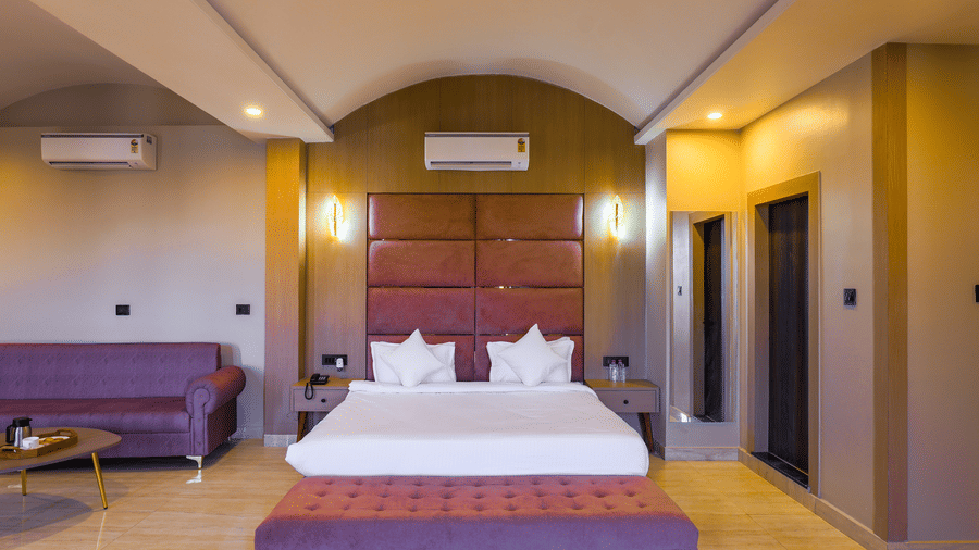 The Suite bedroom with a double bed, a large sofa, a coffee table, and wooden flooring at Grassfield Riveria Resort.