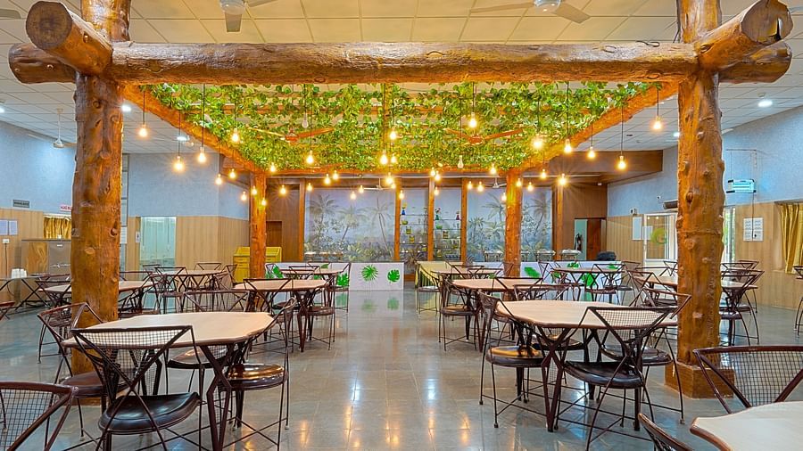 A well-lit restaurant with tables and chairs and light bulbs hanging from the ceiling at Greens Inn - Best Dining Experience in Hyderabad.