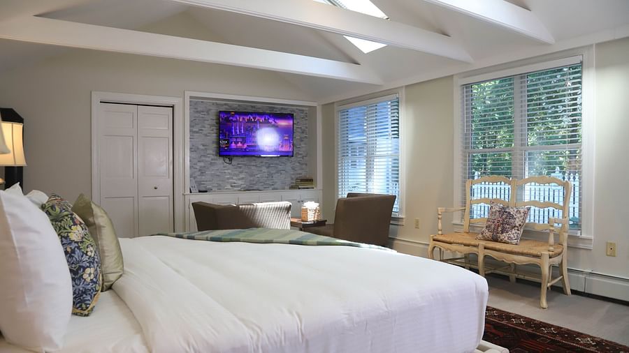 Hotel room with white bed, TV, and large windows at Hartstone Inn