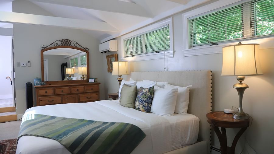Hotel bedroom with green throw blanket and dresser at Hartstone Inn.