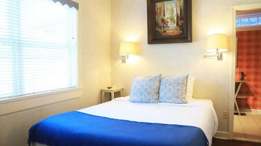 Bedroom with a blue throw, white bedding, and framed art at Hartstone Inn.