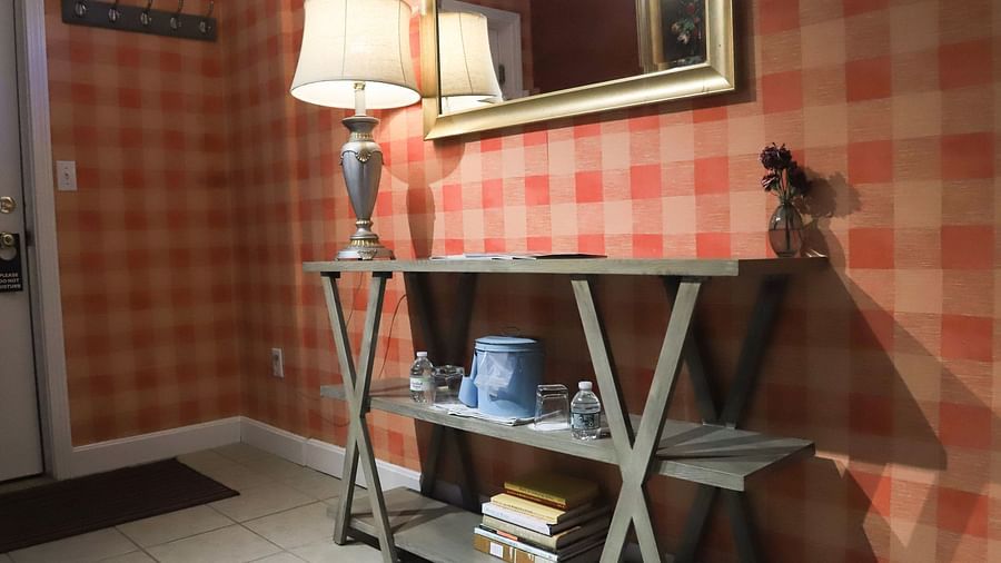 Room with checked wallpaper, a mirror on the wall, and lamp on the table at Hartstone Inn.