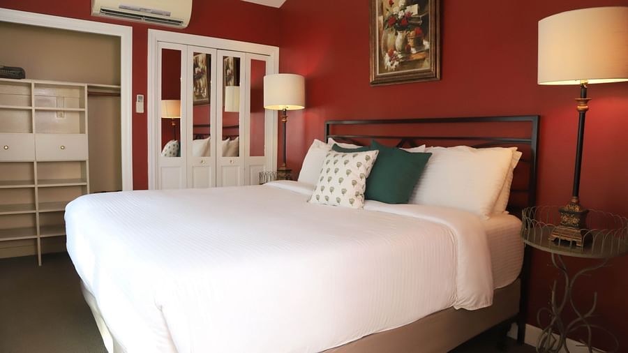 Hotel room with red walls, bed, and a lamp beside the bed at Hartstone Inn.