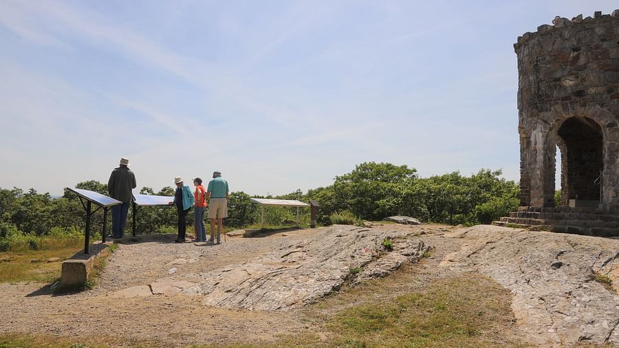 Visitors standing near a stone structure on a grassy hill near Hartstone Inn.