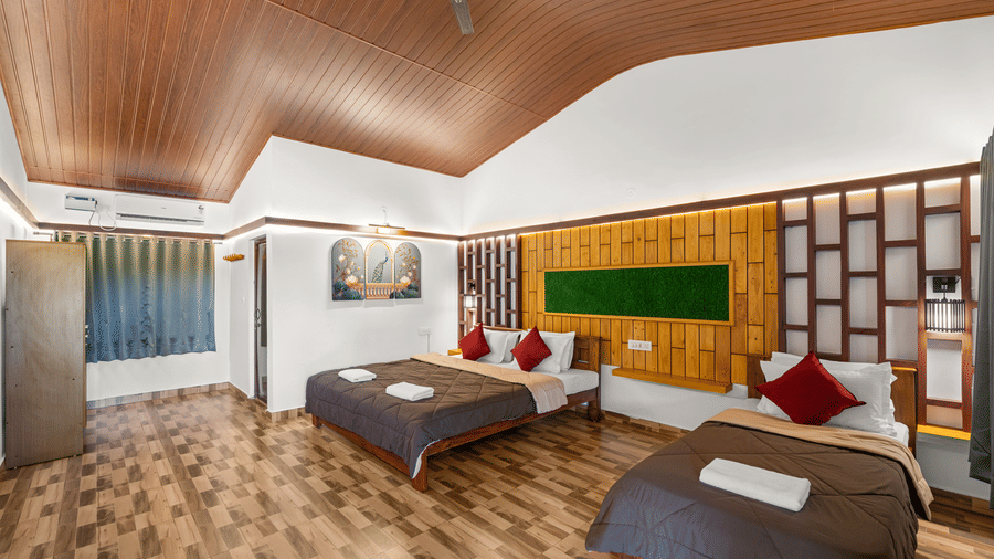 Spacious Room at Hatti Eden Coorg featuring multiple beds, wooden interiors, air conditioning, contemporary décor and ample space, ideal for families and groups seeking a comfortable stay.