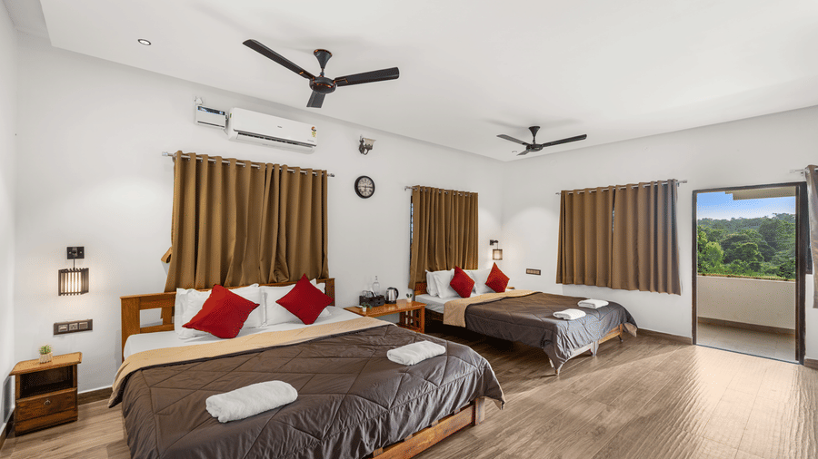 Spacious Quad Room With Forest View at Hatti Eden Coorg, with double beds and a blue sofa.