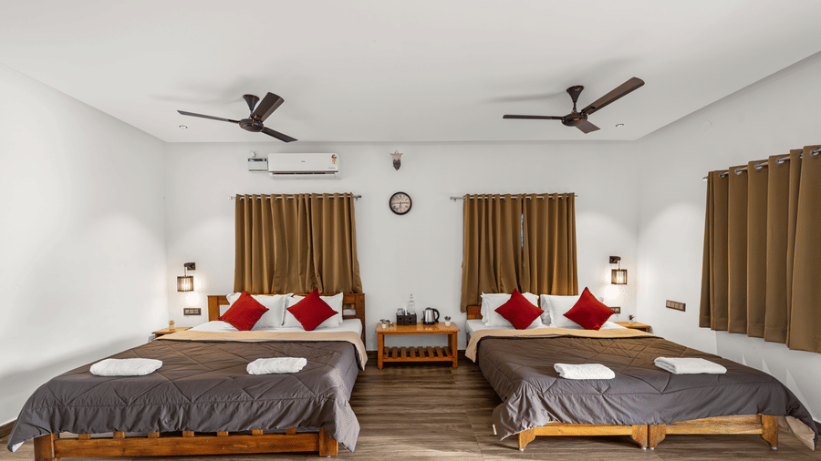 Two double beds with red cushions in the Quad Room With Forest View, Hatti Eden Coorg.