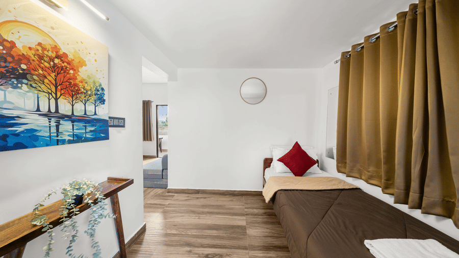 Single bed nook with colorful wall art in the Quad Room With Forest View at Hatti Eden Coorg.