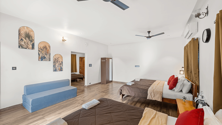 Overview of the Quad Room With Forest View at Hatti Eden Coorg, with wooden floors and double beds.