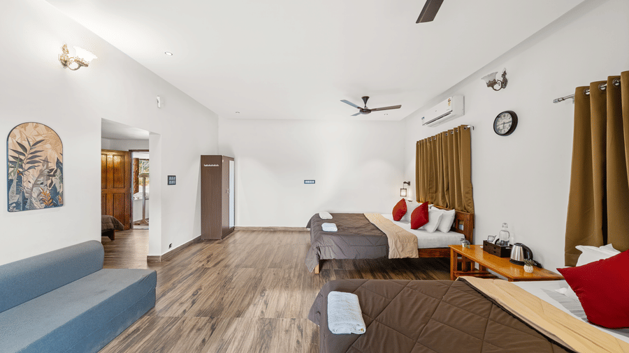 Quad Room With Forest View at Hatti Eden Coorg, showing double beds, sofa, and balcony exit.