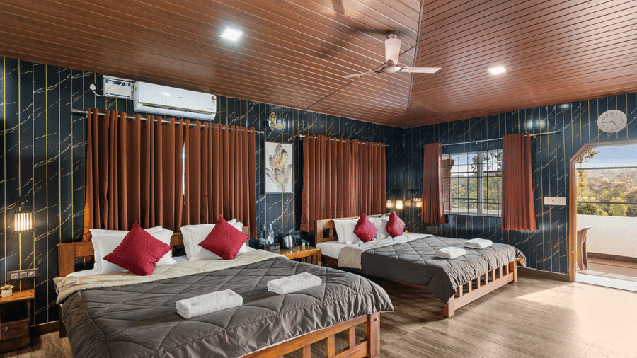 Double beds against dark accent wall in Quad Room With Forest View at Hatti Eden Coorg.