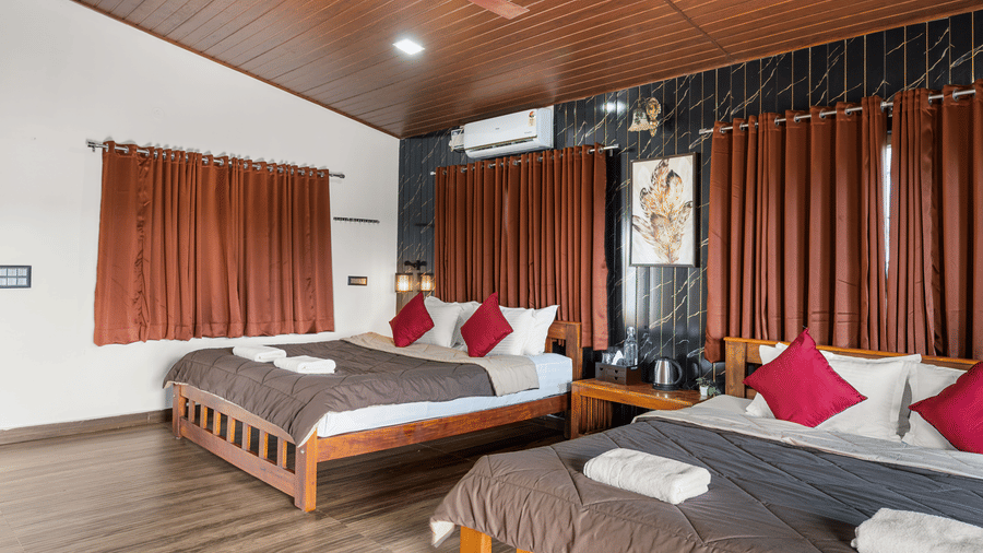 Two double beds with red cushions in Quad Room With Forest View, Hatti Eden Coorg.